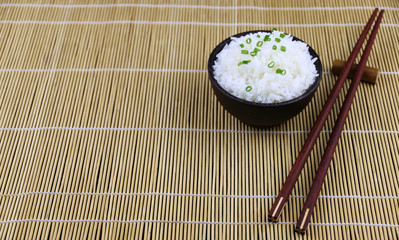 Japanese rice in wood bowl And wooden chopsticks On the Bamboo mat table Asian food