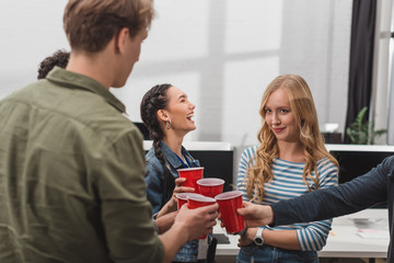 young attractive people clinking cups at modern office