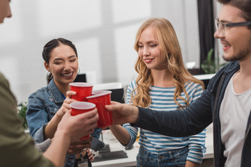 young attractive people clinking cups at modern office
