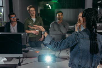 Fototapeta premium young people watching presentation in modern office, woman pointing on screen