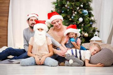 Photo of happy family in Santa caps at Christmas tree