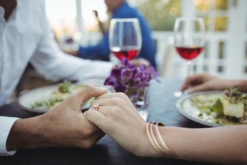 Couple holding hands while having meal
