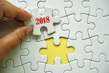 Fototapeta premium A hand holding a piece of puzzle with a words 2018. Conceptual image for incoming new year 2018.