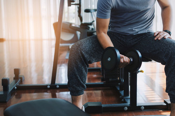 muscular asian young handsome man doing the exercises with dumbbell at biceps in fitness gym,...