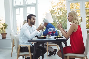 Couple using mobile phone while having meal