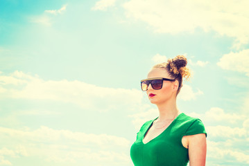 Pretty, Sexy American Lady under sunny sky in hot summer, wearing sunglasses, dressing in green, looking forward, confident and successful. filtered effect. Copy Space..