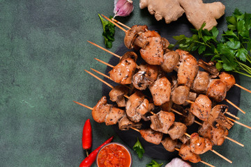 Barbecue of chicken with mushrooms on a green concrete background.