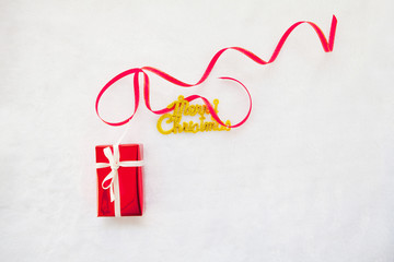 small red gift box and gold merry christmas text with red ribbon