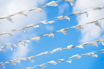 Garland of white flags of triangular shape, pennants in blue sky. City street holiday. Sea, marine theme. Modern background, banner design. Fest, celebration concept