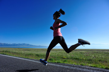 Young fitness sporty woman running on country road