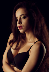 Fototapeta na wymiar Seductive brunette woman with bright makeup and long hair posing in black bra. Shadow and light