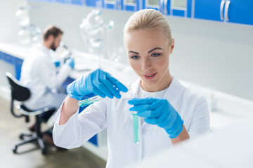 Nice cheerful woman looking at the test tubes