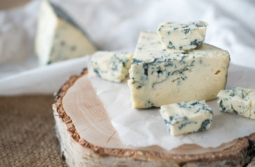 Tasty blue cheese on a wooden background and burlap. Dorblu cheese pieces