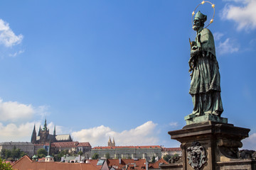 Fototapeta na wymiar Sculpture on Charles Bridge with the cityscape of Prague on the background