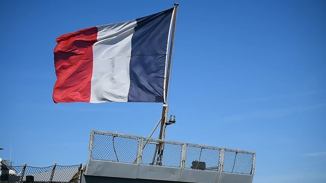 French frigate tied to a dock  in a harbor 