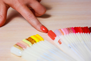 Female finger choosing nail color. Woman index finger indicating on pink color of nail color sample.