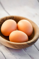 eggs in a wooden bowl on the table from the old boards close up