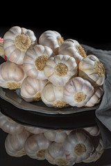 String of french pink garlic on old tin plate on black background