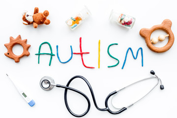 Childhood diseases. Word autism near stethoscope, pills, toys on white background top view