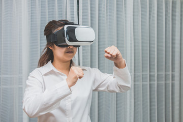 A woman wearing and playing boxing game on virtual reality glasses, Innovation technology