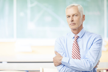 Male teacher in the school. Shot of a senior male teacher standing in the lecture hall in front of...