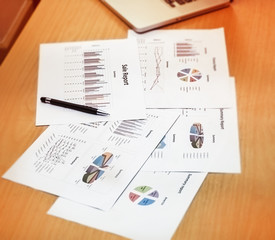 Closeup pen and  paper work at office hour,investment chart and office work,busy hour work time of the business worker,blurry light aroundl