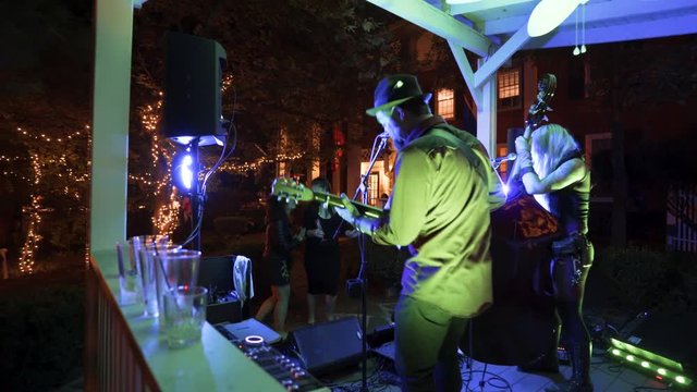 Women dance as a blues band plays music at an outdoor cafe at night.