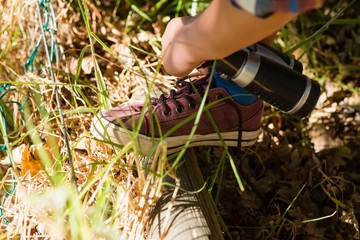 Boy tying shoelace in the forest