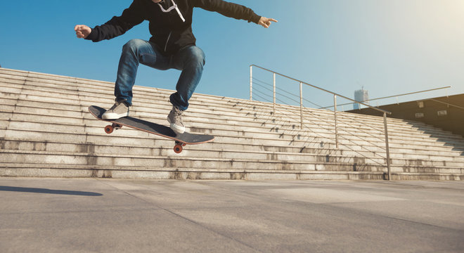 Skateboarder jumping on city stairs with skateboard