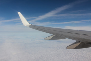  Shining in the sun a passenger plane wing against a blue sky and whiteness of clouds