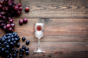 Glass with wine sediment and grape on dark wooden background top view copyspace