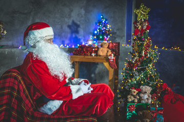 Santa claus Sit on chair think about plan for sent gift box for give children at home