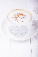 White mood. White cup of coffee cappuccino with Ceylon cinnamon and white heart on a wooden background