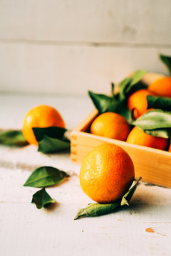 Fresh tangerines in an old box with leaves. On wooden background. Free space for text . Top view
