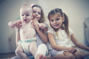 Little girls with baby brother poses to camera.