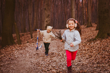 Little boy and girl walk with willow branches outside in the rays of evening sun