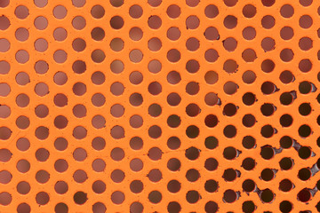 Orange painted circle perforated metal panel texture and background