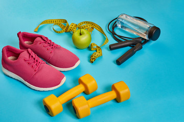 Flat lay of dumbbell, bottle of water, jump rope and sneaker, sport equipments, fitness items, top view