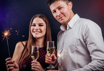 Couple celebrating New Year's eve drinking champagne and lighting up sparklers