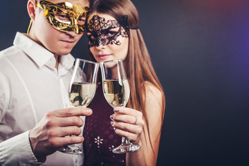 Couple celebrating New Year's eve drinking champagne on masquerade party - obrazy, fototapety, plakaty