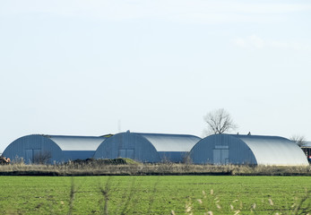 Three hangars in the field. Hangars from galvanized iron.