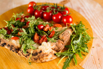 Pizza with cherry tomatoes on bed of rocket