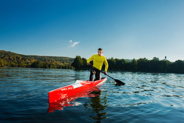 Strong young man with his kayak on a sunny day on a lake. 