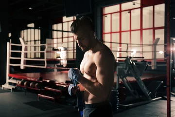 Keuken foto achterwand Vechtsport Mannelijke bokser die handwraps aanbrengt terwijl hij zich voorbereidt op de training in de sportschool