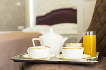 Fototapeta na wymiar Two white mugs on a tray white bed, breakfast concept