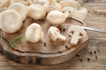 Fresh champignon mushrooms on wooden board