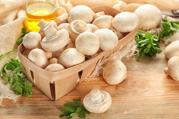 Basket with fresh champignon mushrooms on table