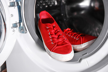 Pair of red sneakers in washing machine, closeup