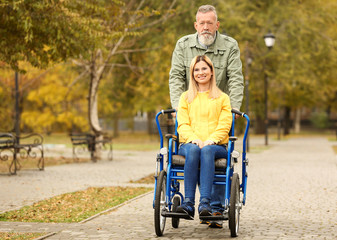 Senior man with his daughter in wheelchair outdoors on autumn day