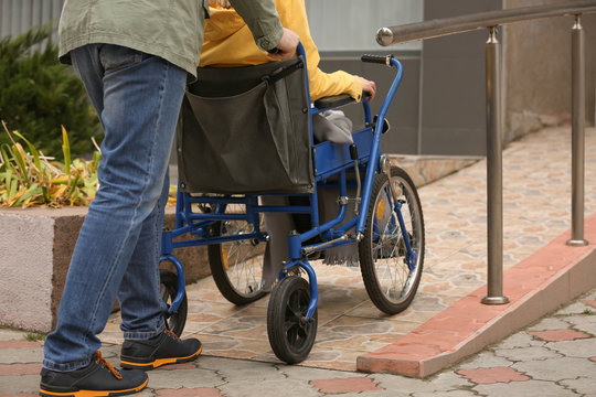 Man with his wife in wheelchair on ramp outdoors